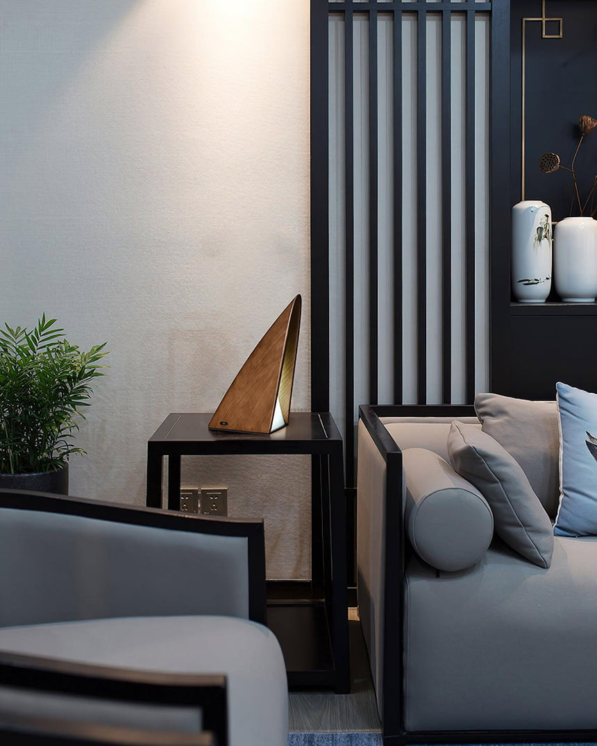Small bedside lamp lit on a dark console in a living room corner