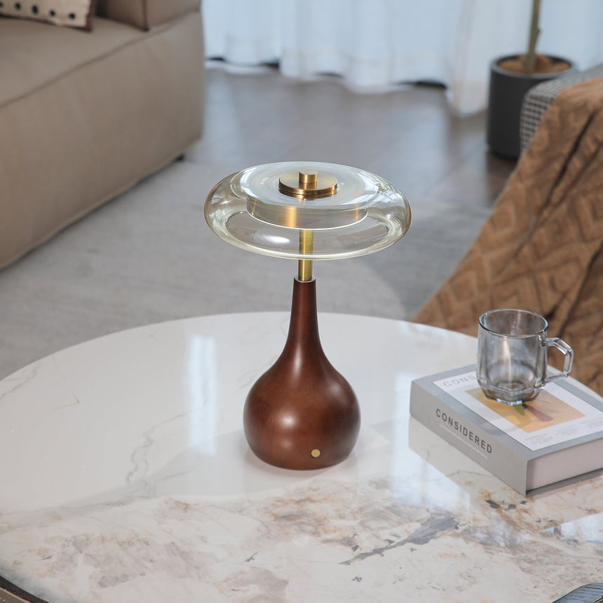 Small table lamp lit on a marble table seen across a pale room