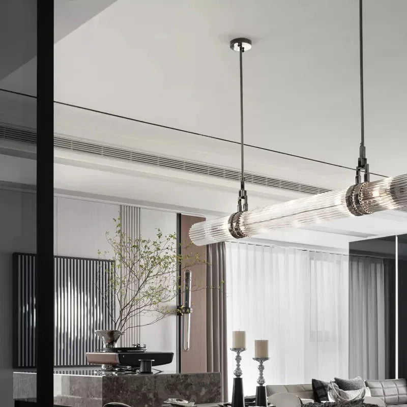 The row of smoked glass tubes lit above a dining table in a pale room