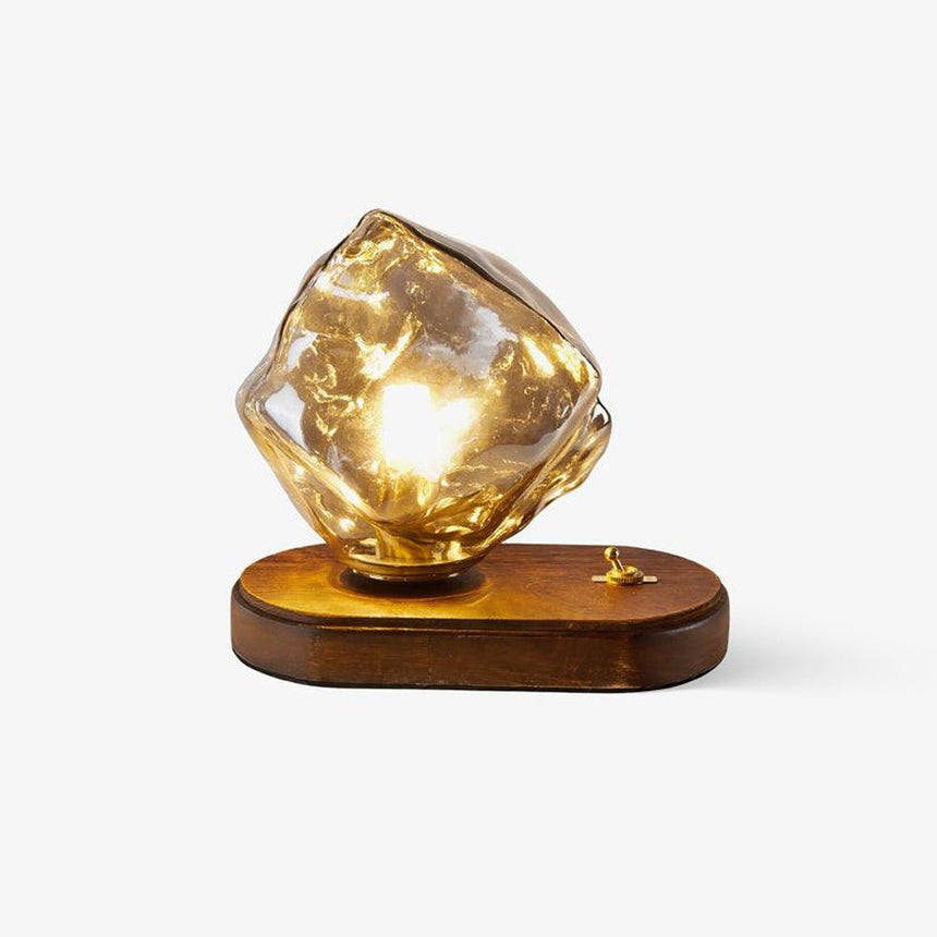 Amber glass ice form lit on a dark wood plinth, plain ground