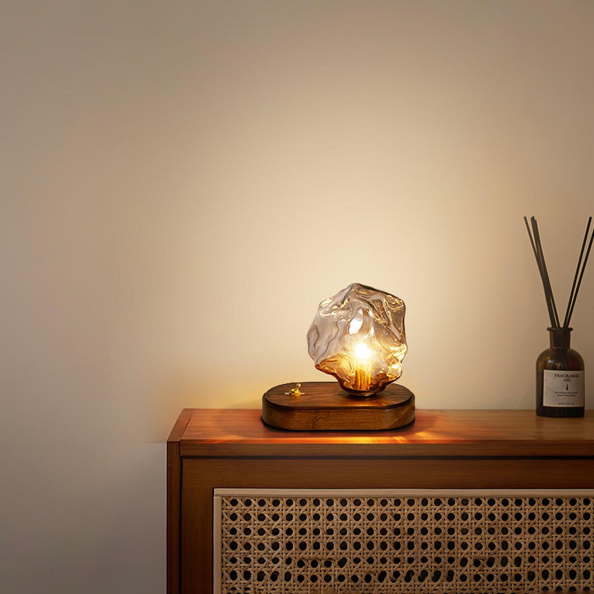 Glass ice form lamp lit on a cabinet beside a reed diffuser