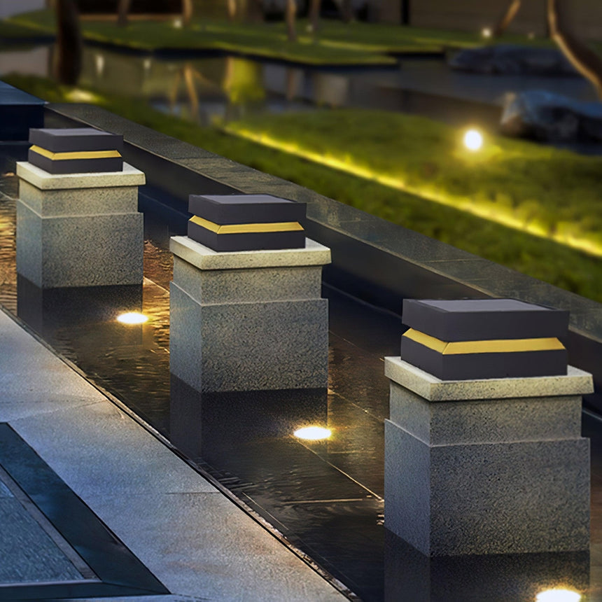A run of lit caps along pillars beside stone steps and planting