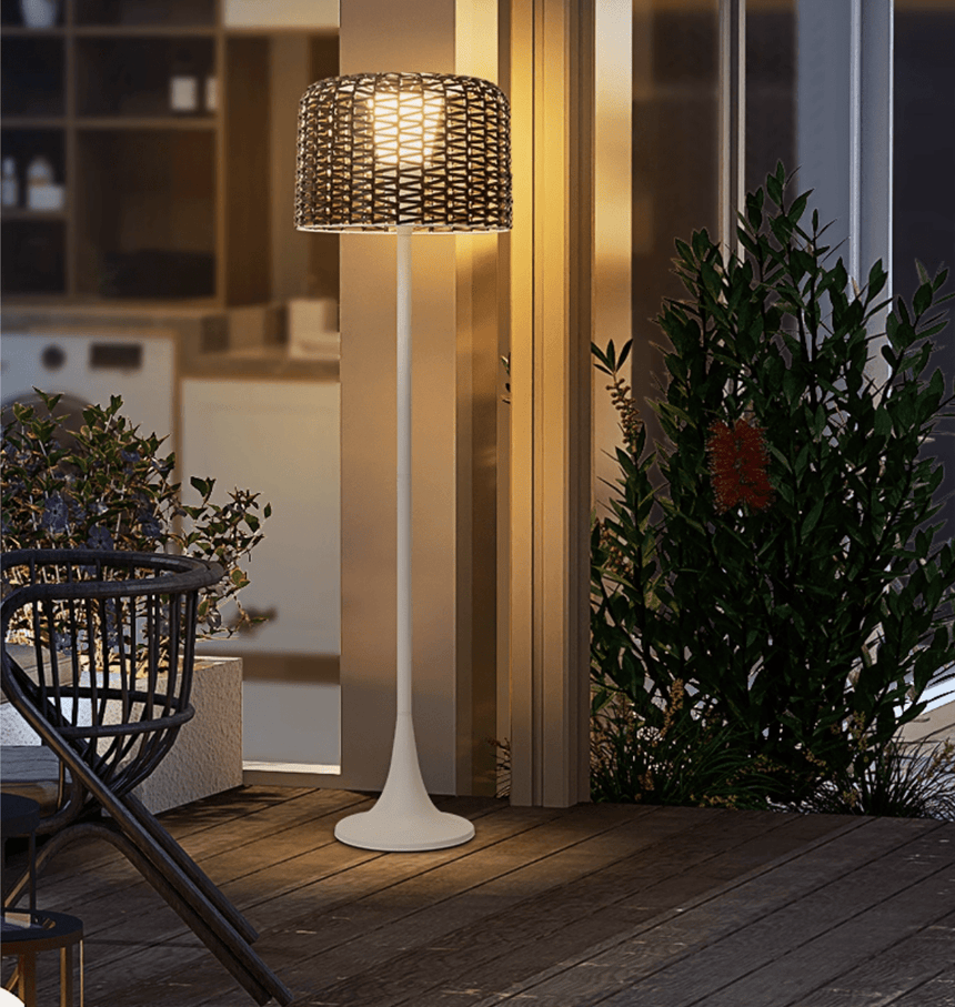 The lamp lit outside glass doors beside potted planting and a chair