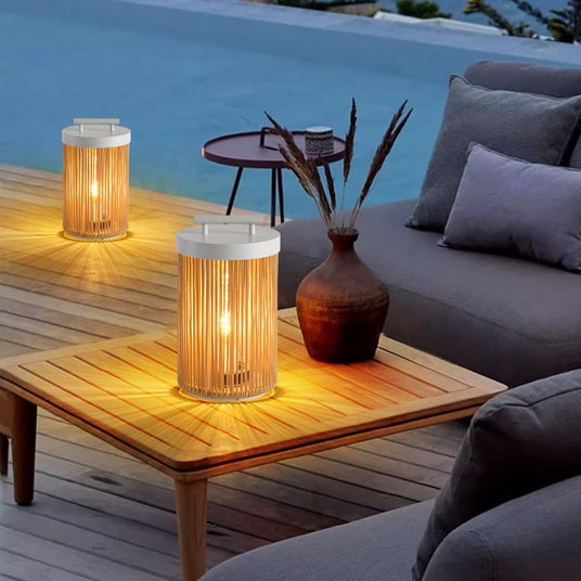 Two lit on a timber table beside an outdoor sofa with pillows