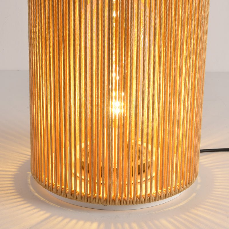 The lit bulb seen through the vertical rattan strands of the column