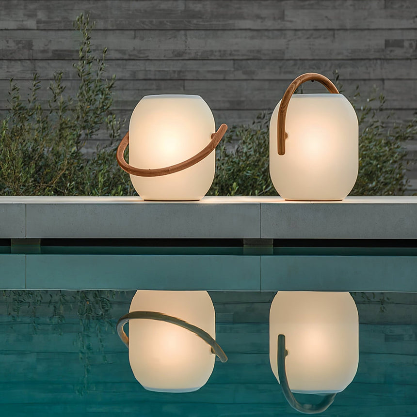 Two lamps lit on a pool edge at dusk with their reflection in the water