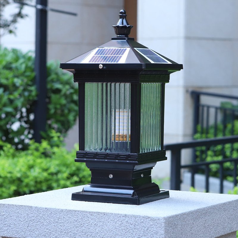 The lantern glowing warm on a cut stone pillar beside a garden path
