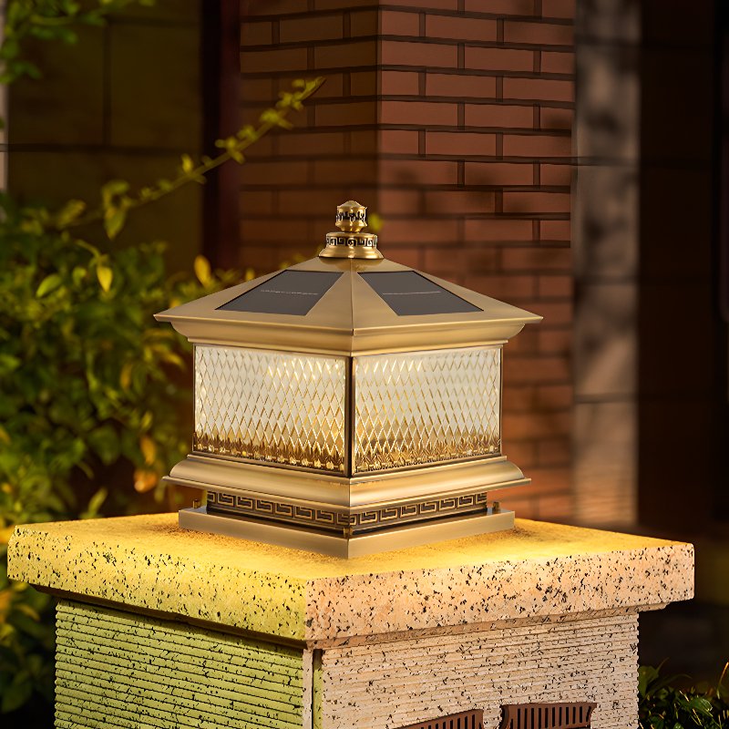 Copper toned lantern lit on a cut stone pillar beside a garden path