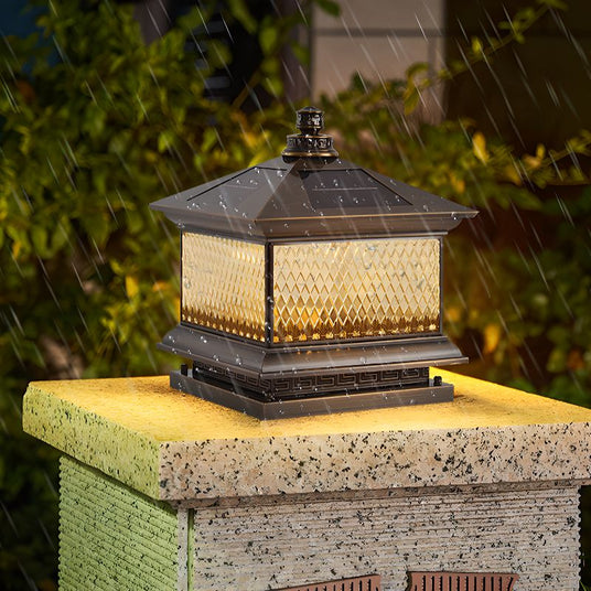 The lantern glowing on a stone pillar with grass and shrubs around it