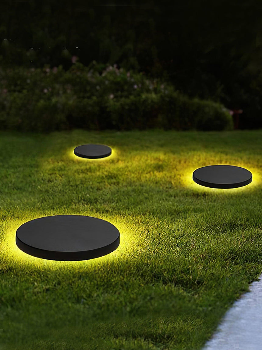 Two lit on dark grass with a soft ring of glow around each disc