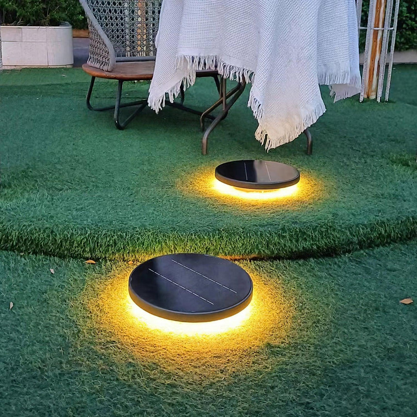 Two lit on a lawn beside a garden table with a white cloth on it