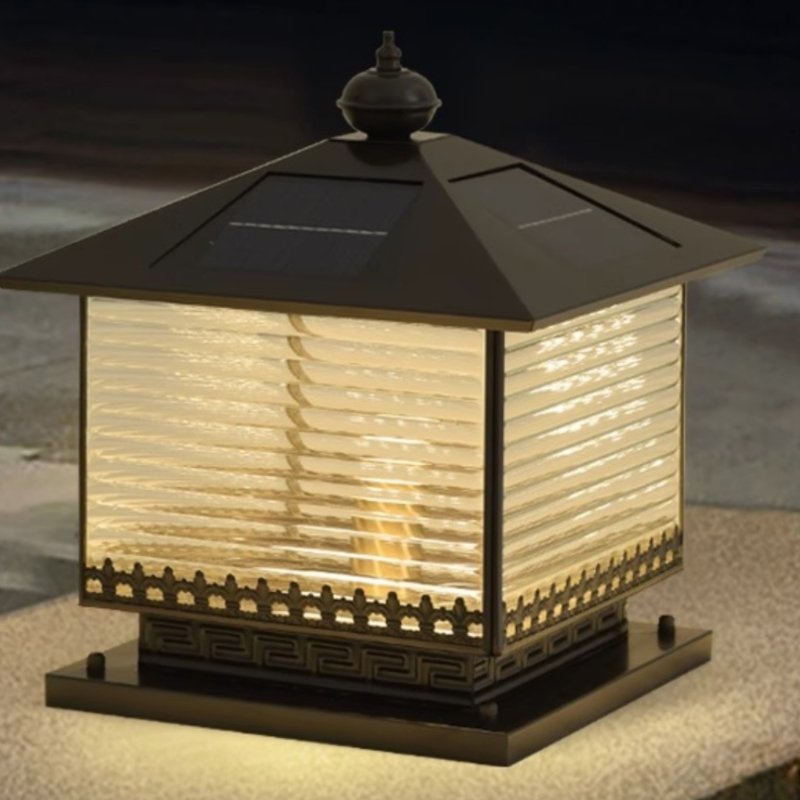 The lantern lit on a masonry pillar with planting in the evening