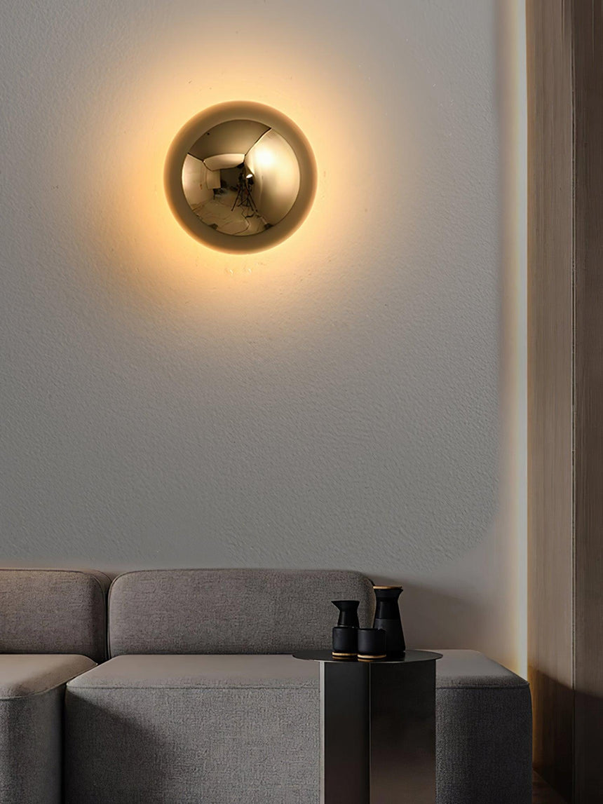 The gold sphere lit above a gray sofa in a warm lit room