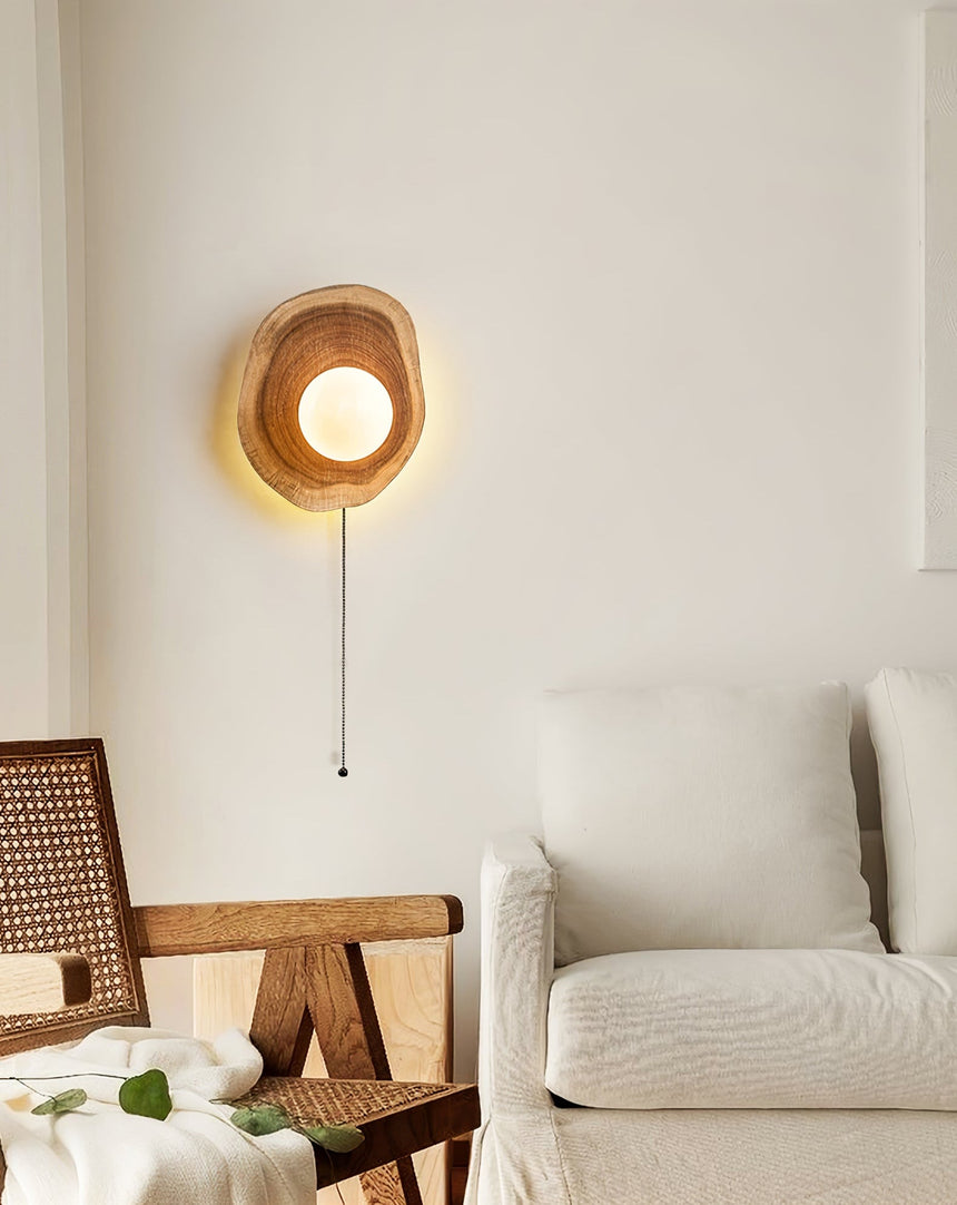 Sconce lit beside a cane chair and a pale sofa in a bright corner