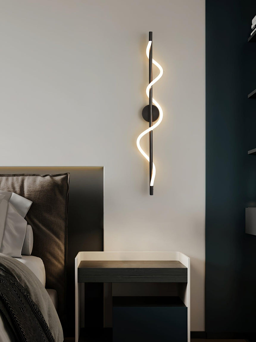 The lit spiral beside a bed with a dark headboard and a small table