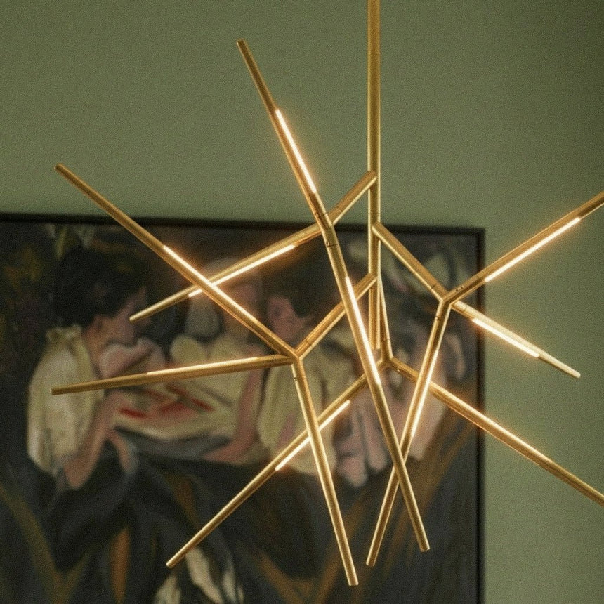The lit gold arms in front of a green wall and a framed painting
