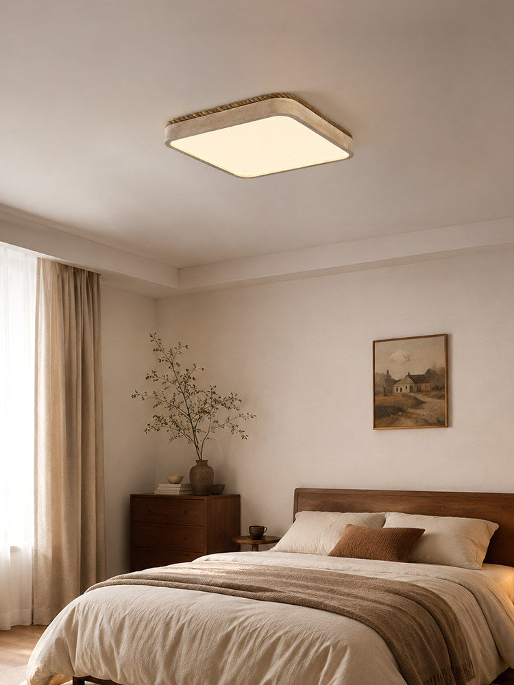 Square travertine ceiling light seen across a bedroom with a wood dresser