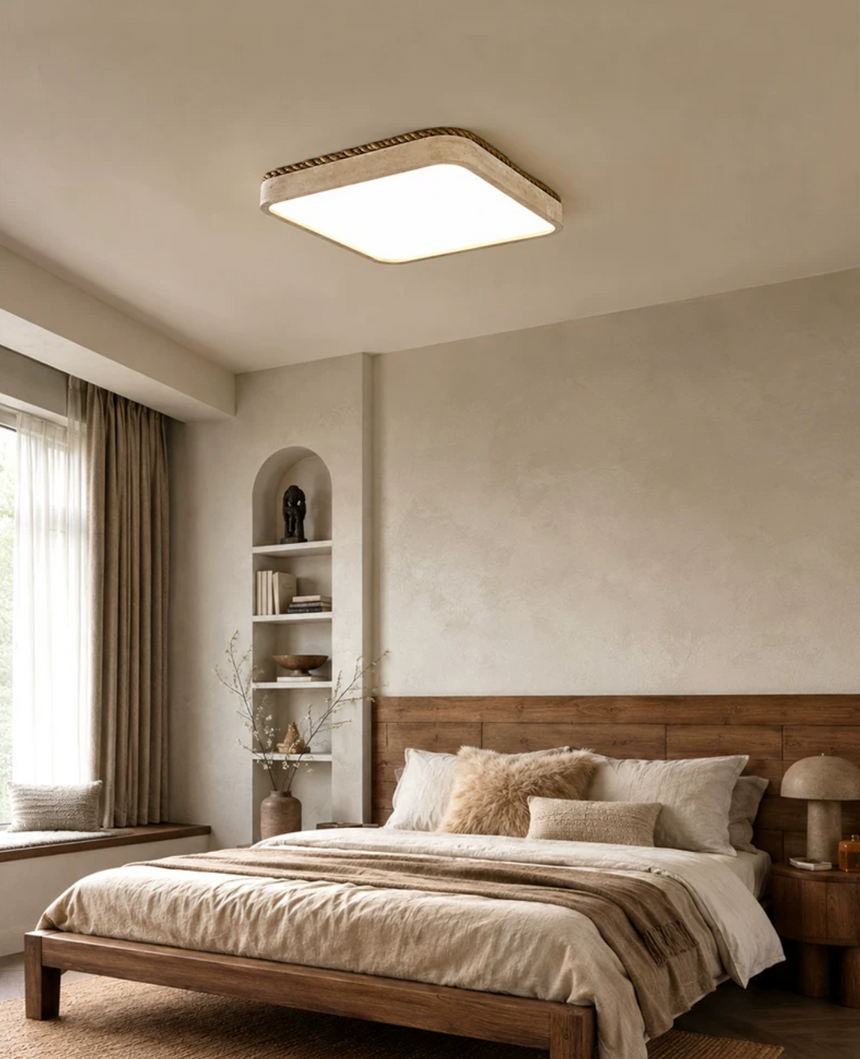 Square travertine ceiling light lit above a bed with a striped throw and an arched niche