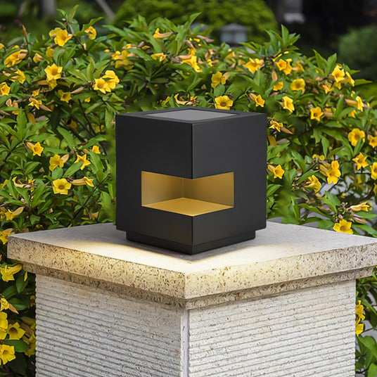The cube lit on a stone pillar with yellow flowers growing beside it