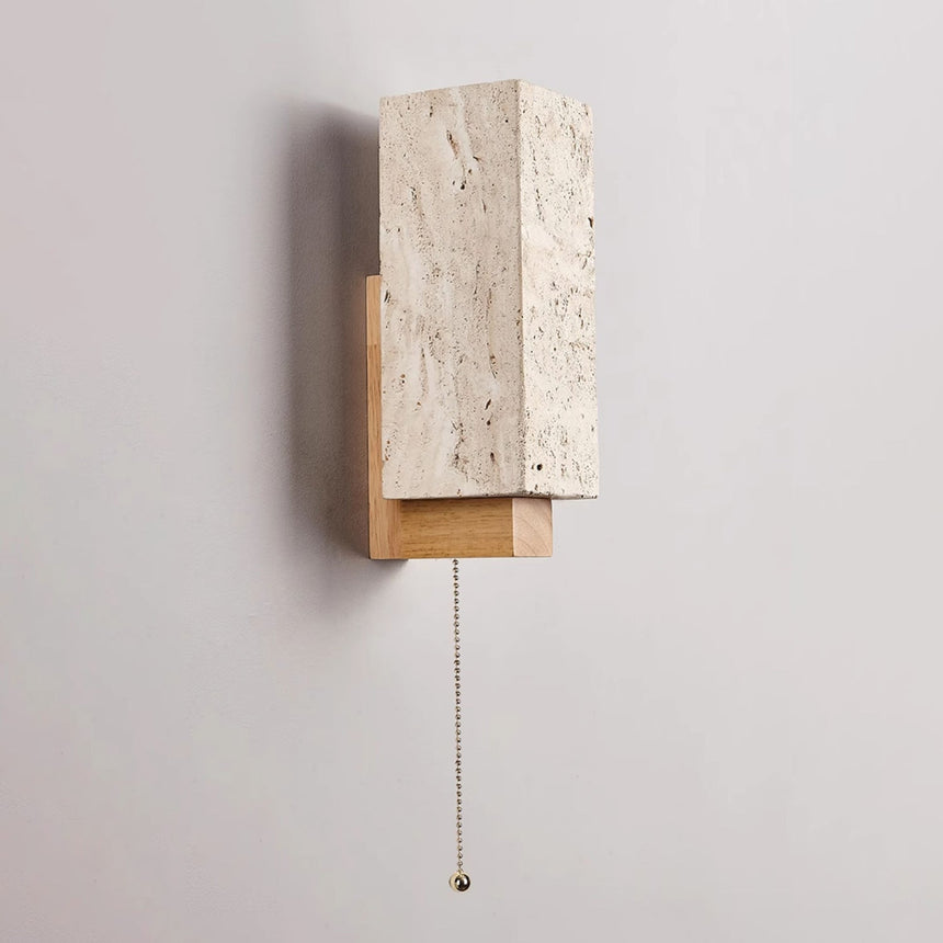 The pull chain hanging from under the wood bracket beside the stone block