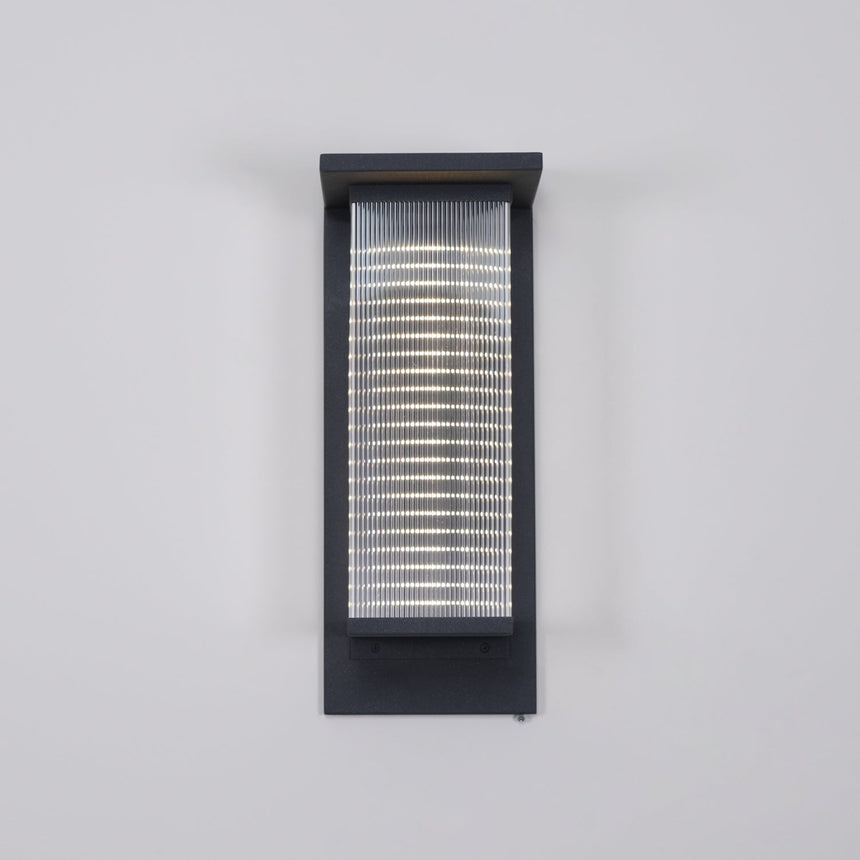 Front view of the lantern on a gray wall with the ribbed panel lit