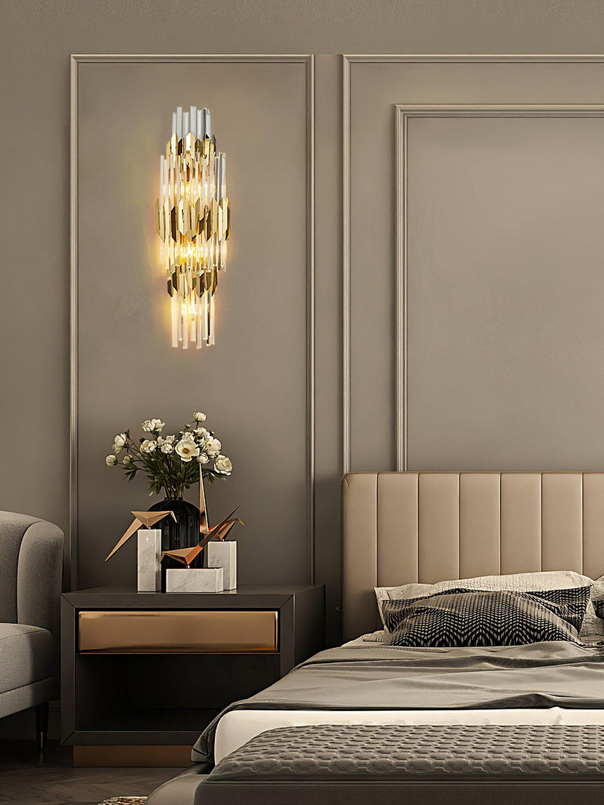 The sconce lit above a nightstand with flowers beside an upholstered bed