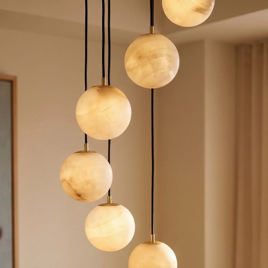 Lit alabaster spheres at four different heights beside a pale curtain