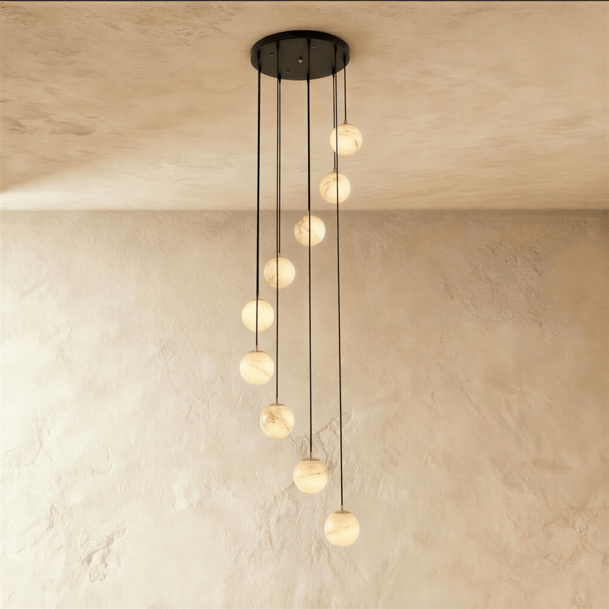 Nine lit alabaster spheres on black cords cut to different lengths