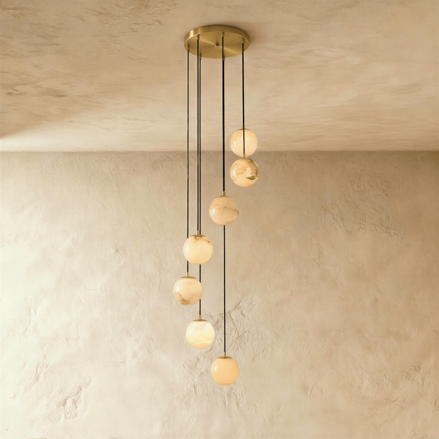 Seven lit alabaster spheres on cords from a round brass ceiling plate