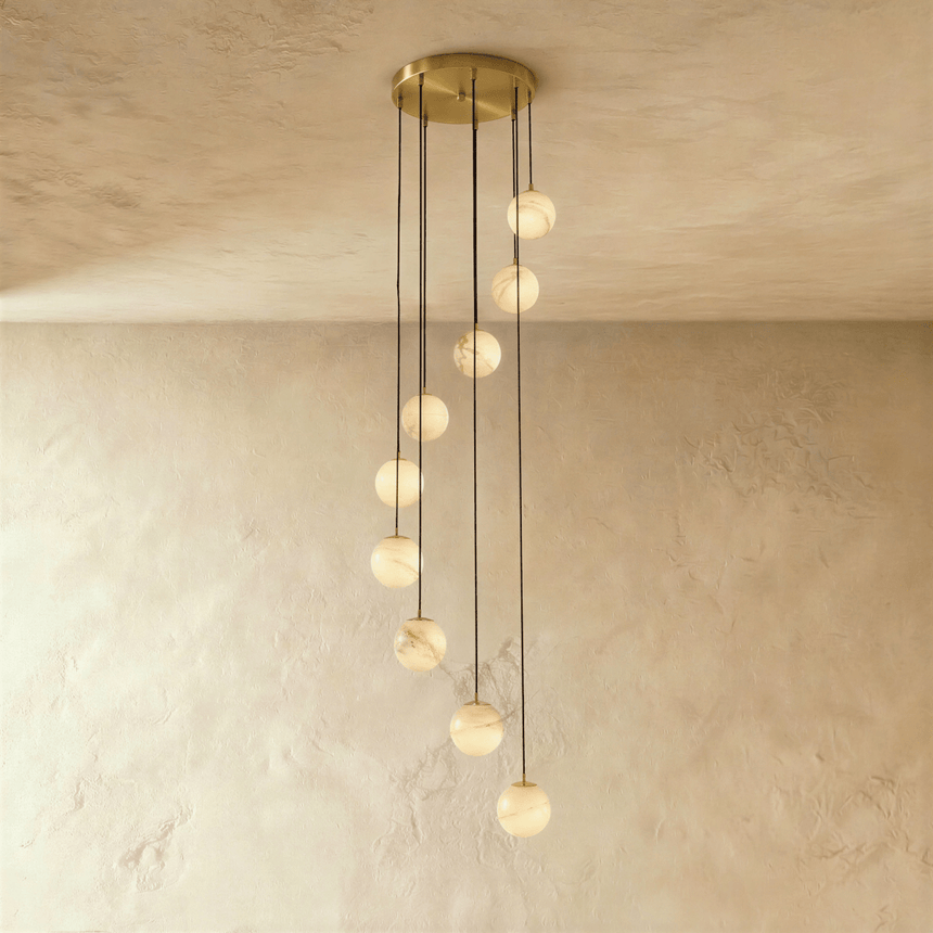 Twelve lit alabaster spheres in a cascade below a wide brass plate