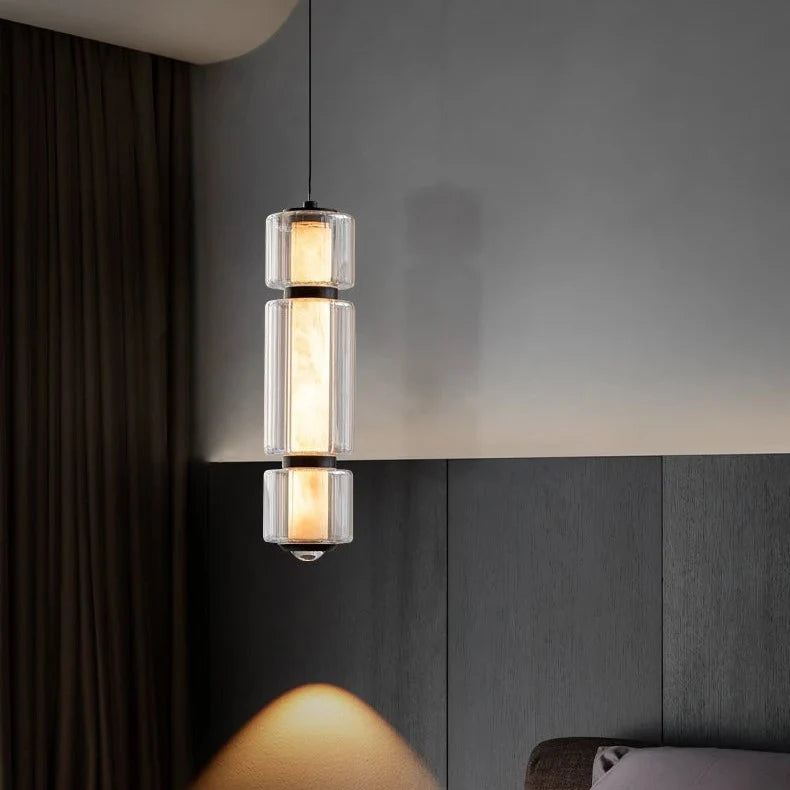 The marble and glass pendant lit beside a bed with a padded headboard