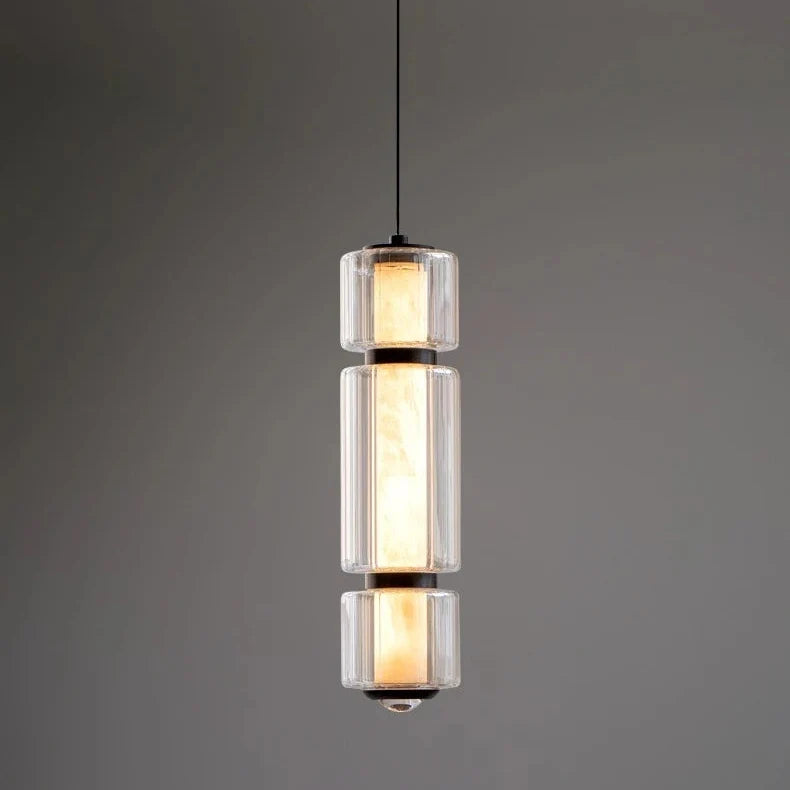 The lit marble cylinder seen against a dark wall with its glass sleeve
