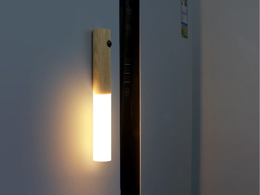 Lit beside a dark doorway, the tube throwing a warm pool down the frame