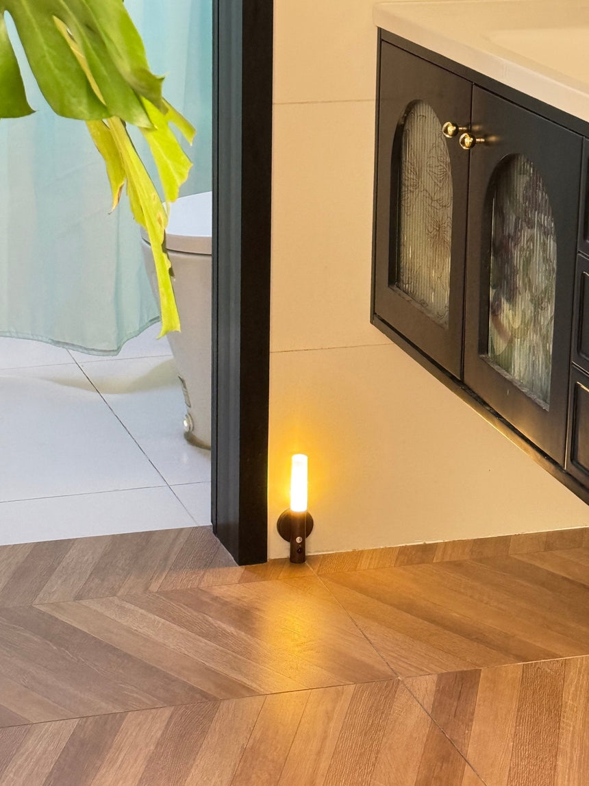 Lit low beside a fireplace on a herringbone floor, the beam washing the boards