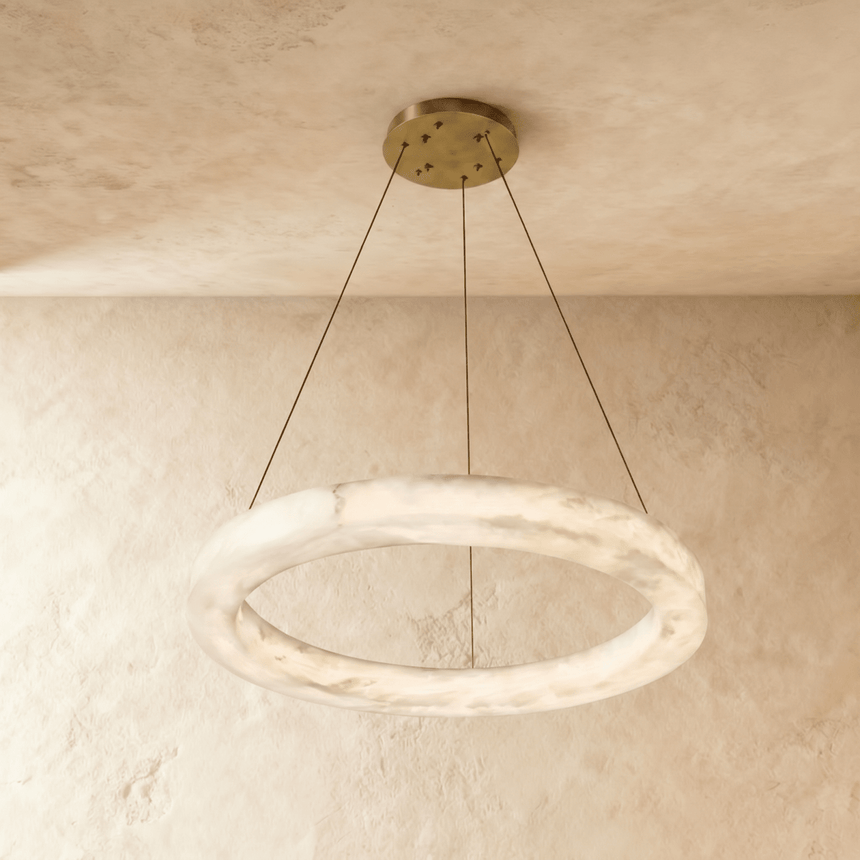A single alabaster ring lit, hung on three thin cables from a brass plate