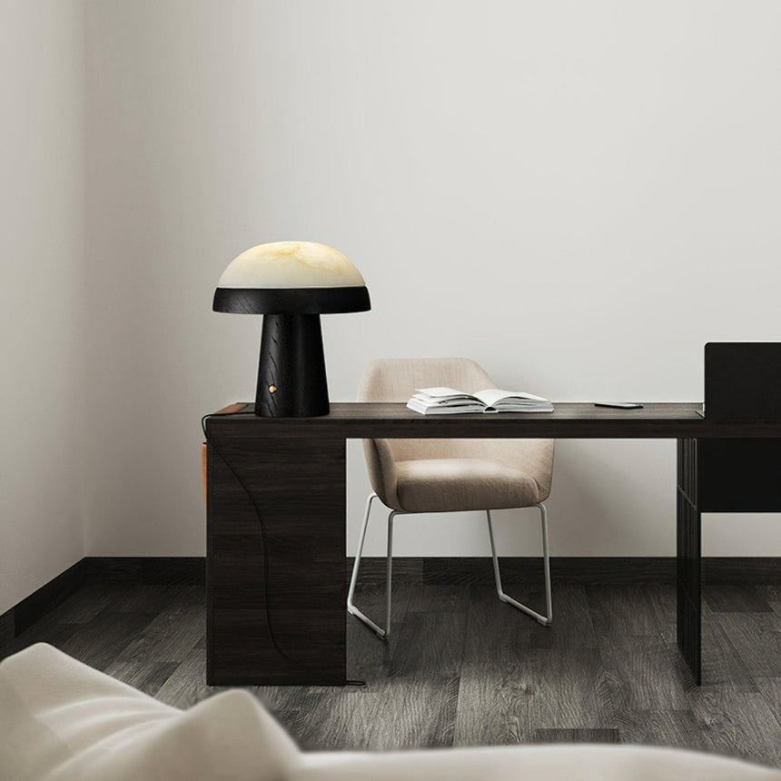 Stone table lamp with a black base lit on a dark desk