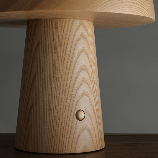 Close view of the brass push button on the wood base of the lamp