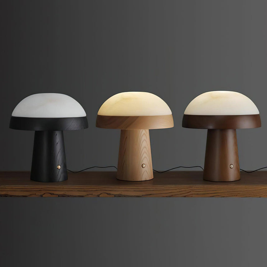 The three finishes of the stone table lamp lit side by side on a bench