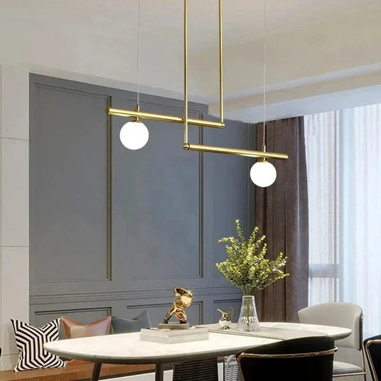 Brass frame with two globes above a dining table beside a bright window