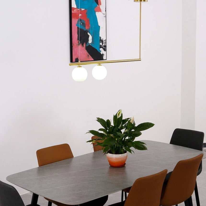 Brass frame above a dark dining table with leather chairs and a plant