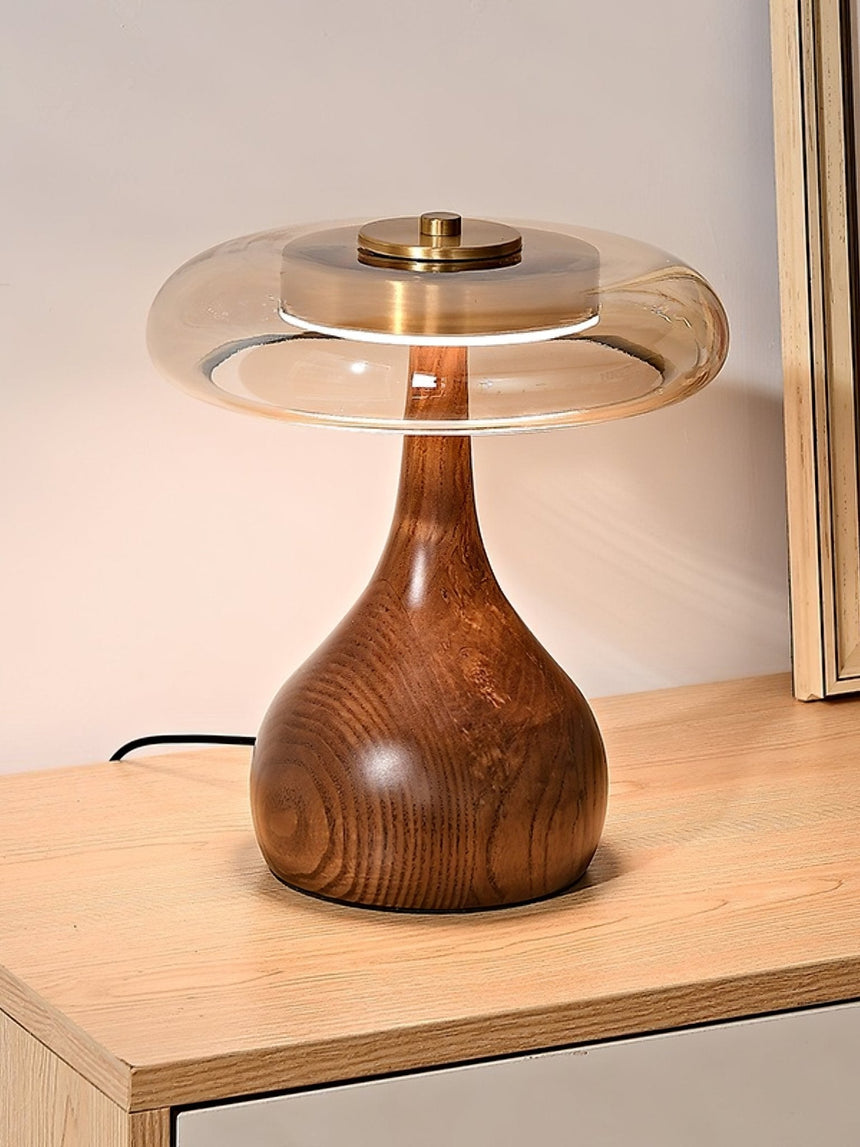 Table lamp with a glass shade lit beside a leaning mirror