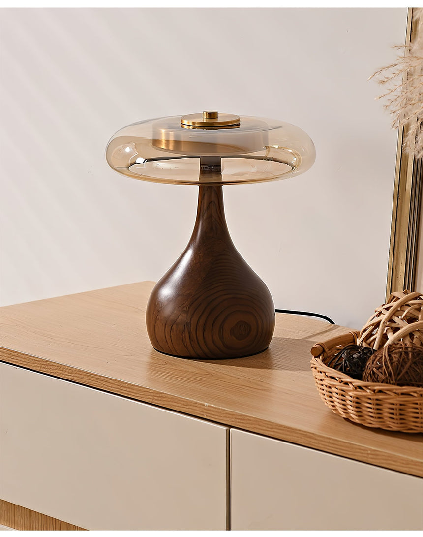 Table lamp with a glass shade unlit on a sideboard, the grain visible