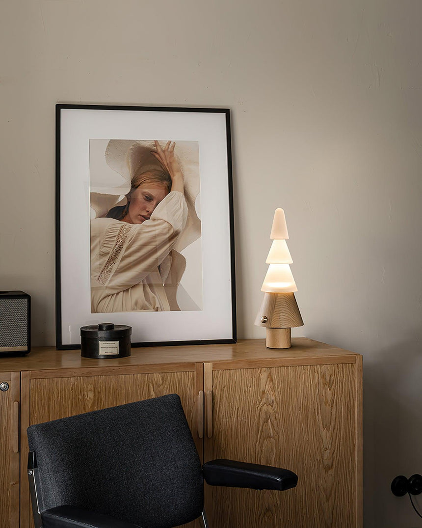 Table lamp with night light lit on a wooden cabinet beside a print