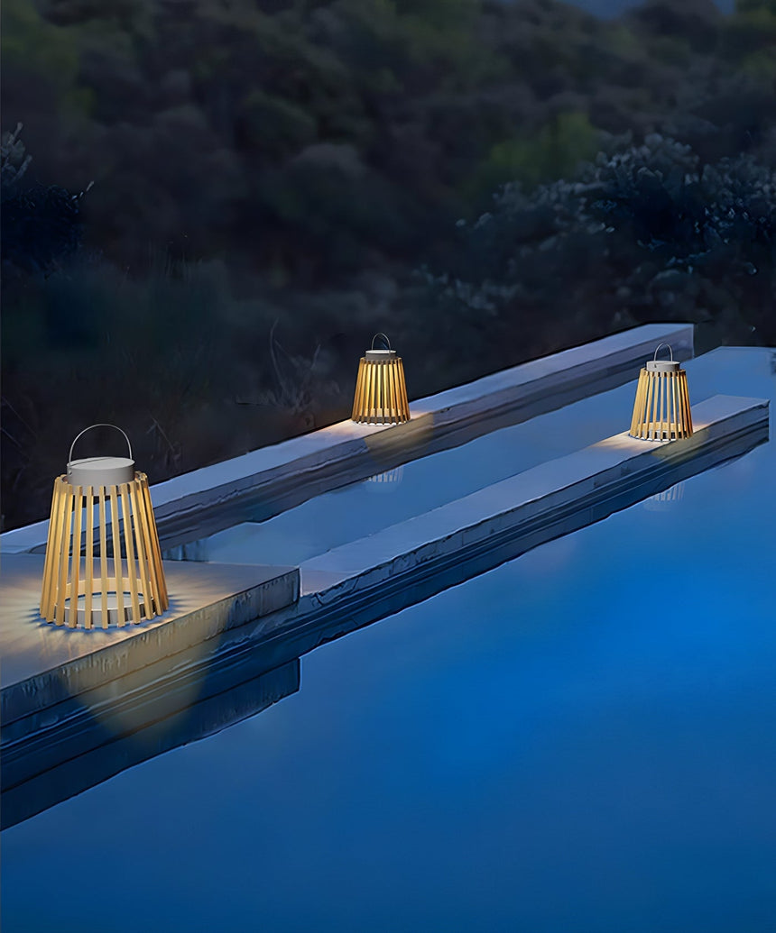 The lantern lit on the coping of a pool with the water lit blue beyond