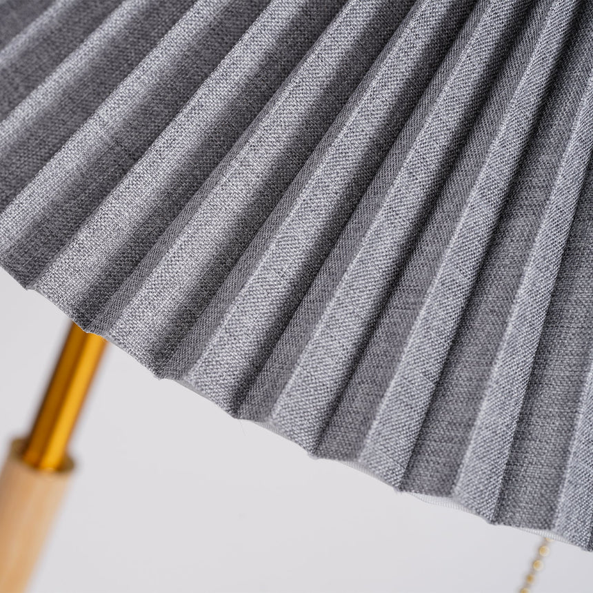 Close view of the gray pleated fabric against the brass pole