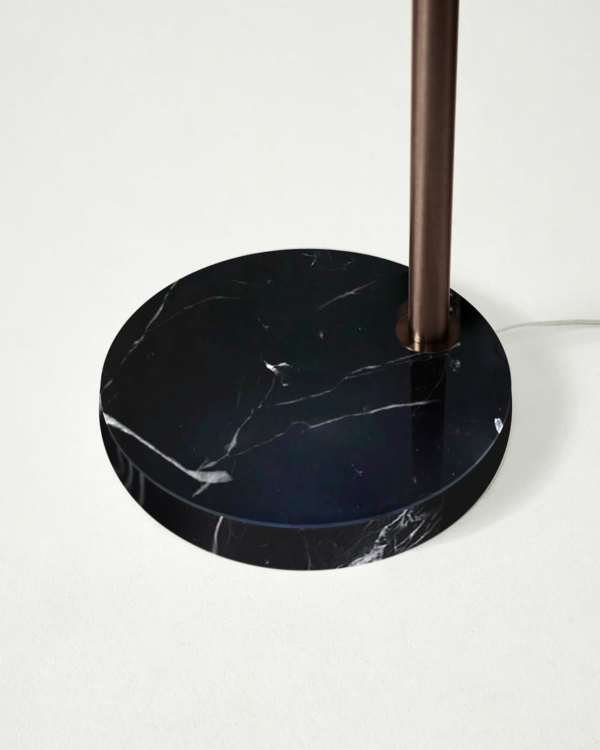 The round black marble base seen close with the bronze pole set into it
