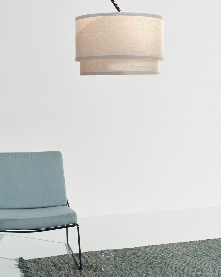 The oatmeal shade above the same blue chair and green rug in a bare room