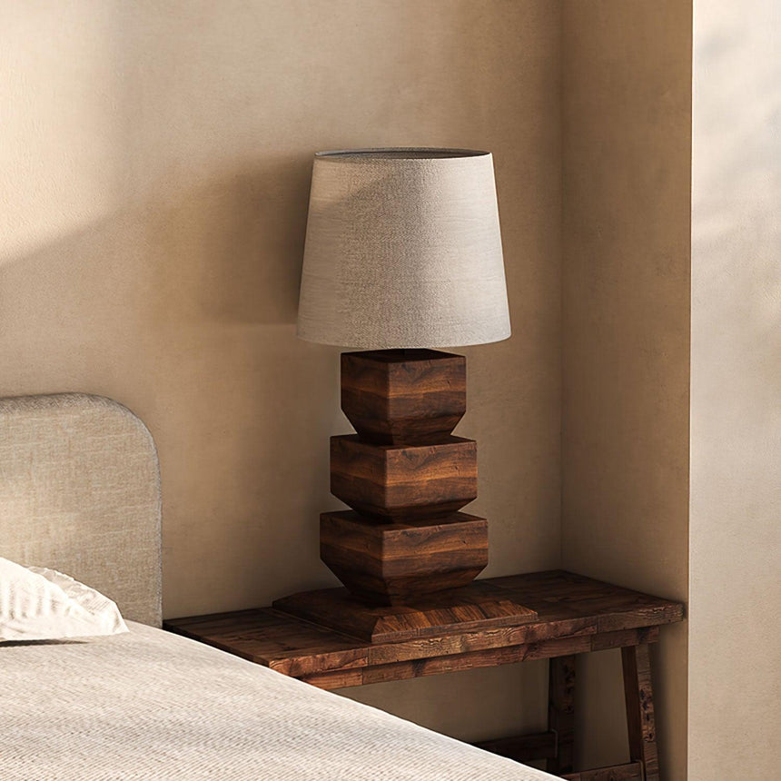 Tall table lamp on a wooden bench beside an upholstered bed head