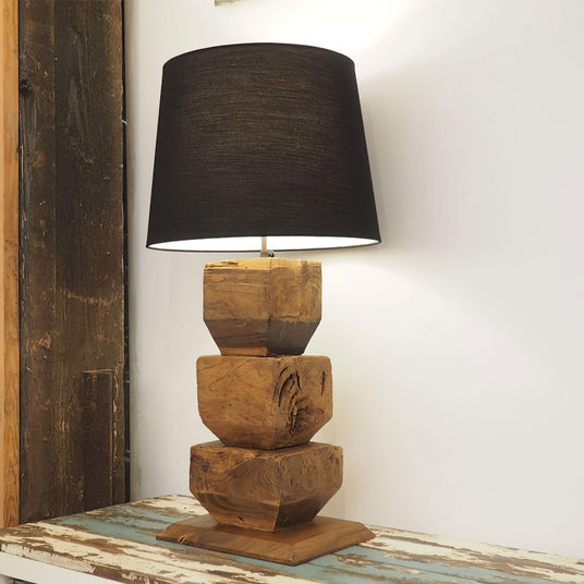 Close view of the black drum shade and the carved wood blocks below it