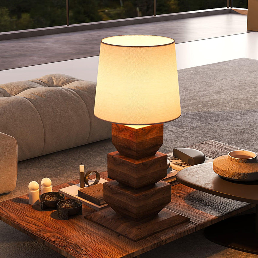 Tall table lamp lit on a wooden table in a living room with a sofa
